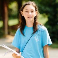 A camper smiles holding her writing notebook.